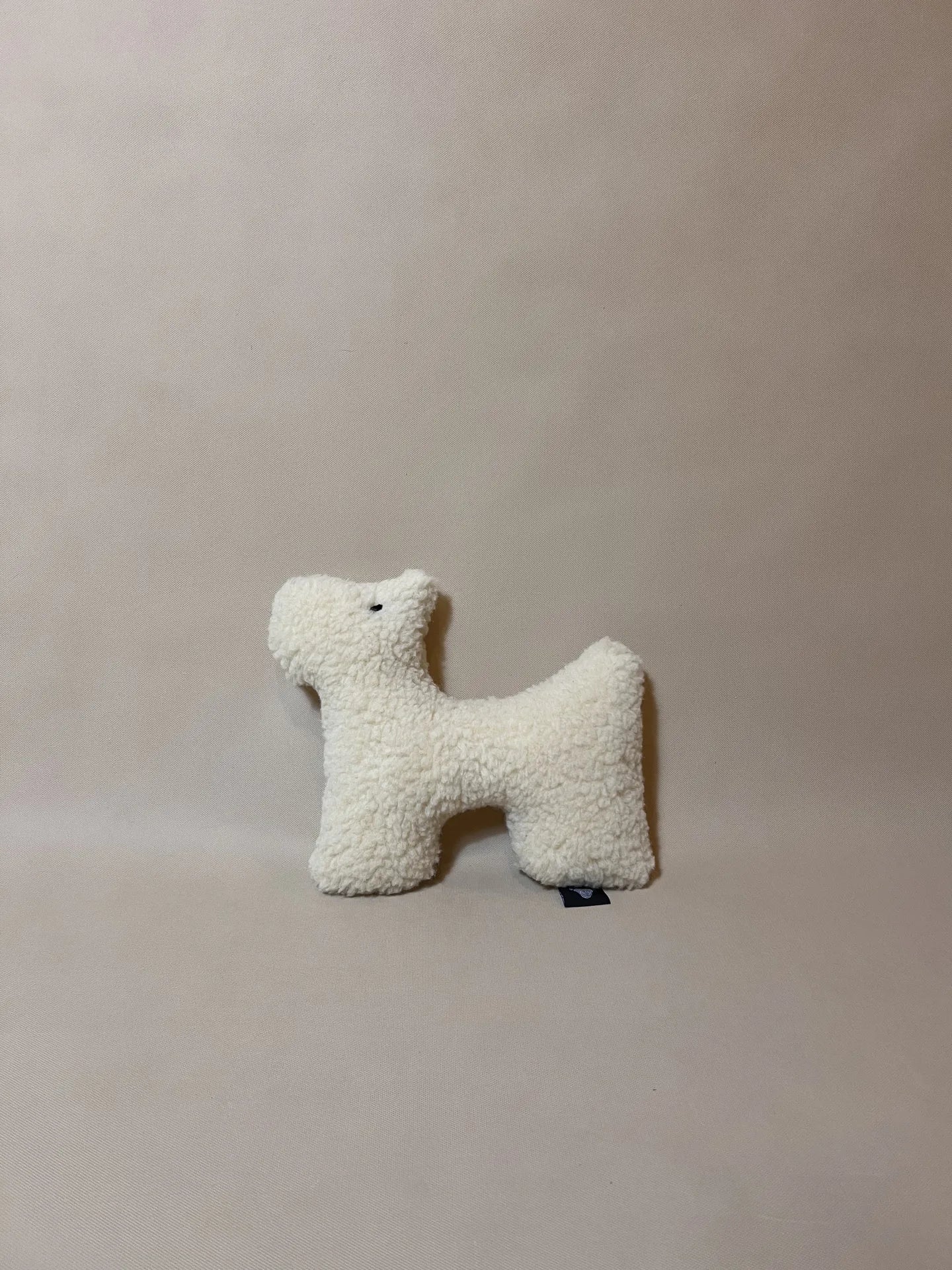 Soft wool plush pet toy featuring a textural boucle loop material for dogs and cats to play and snuggle with.