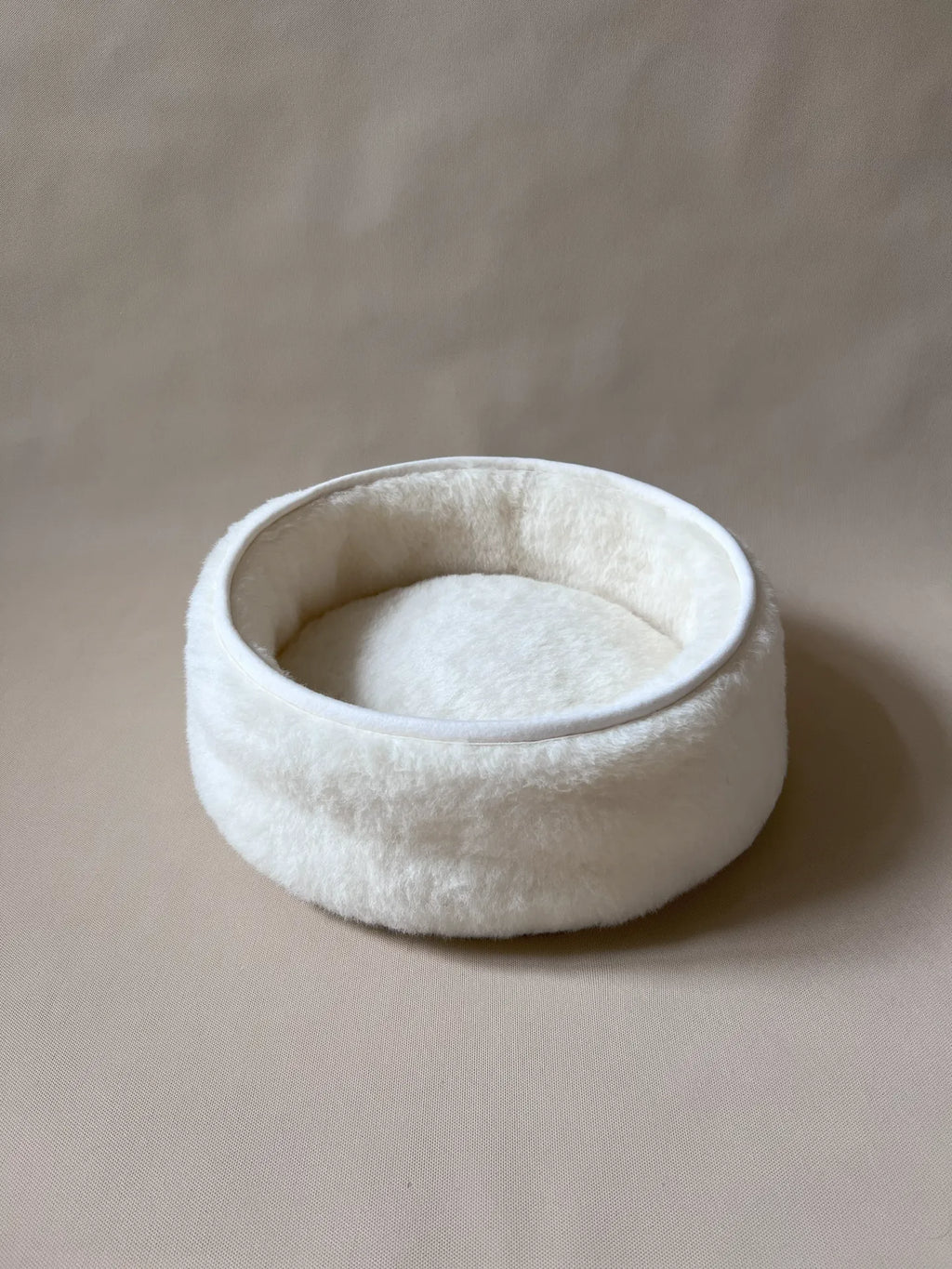 Soft wool and cashmere pet bed by featuring a plush design for comfort in a neutral color.