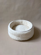Soft wool and cashmere pet bed by featuring a plush design for comfort in a neutral color.
