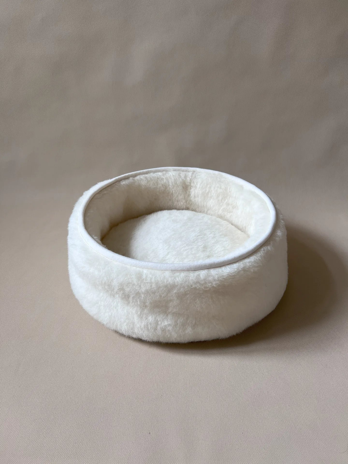 Soft wool and cashmere pet bed by featuring a plush design for comfort in a neutral color.