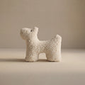 A small wool plush pet toy featuring a bouclé loop textured material, standing on a neutral beige background.