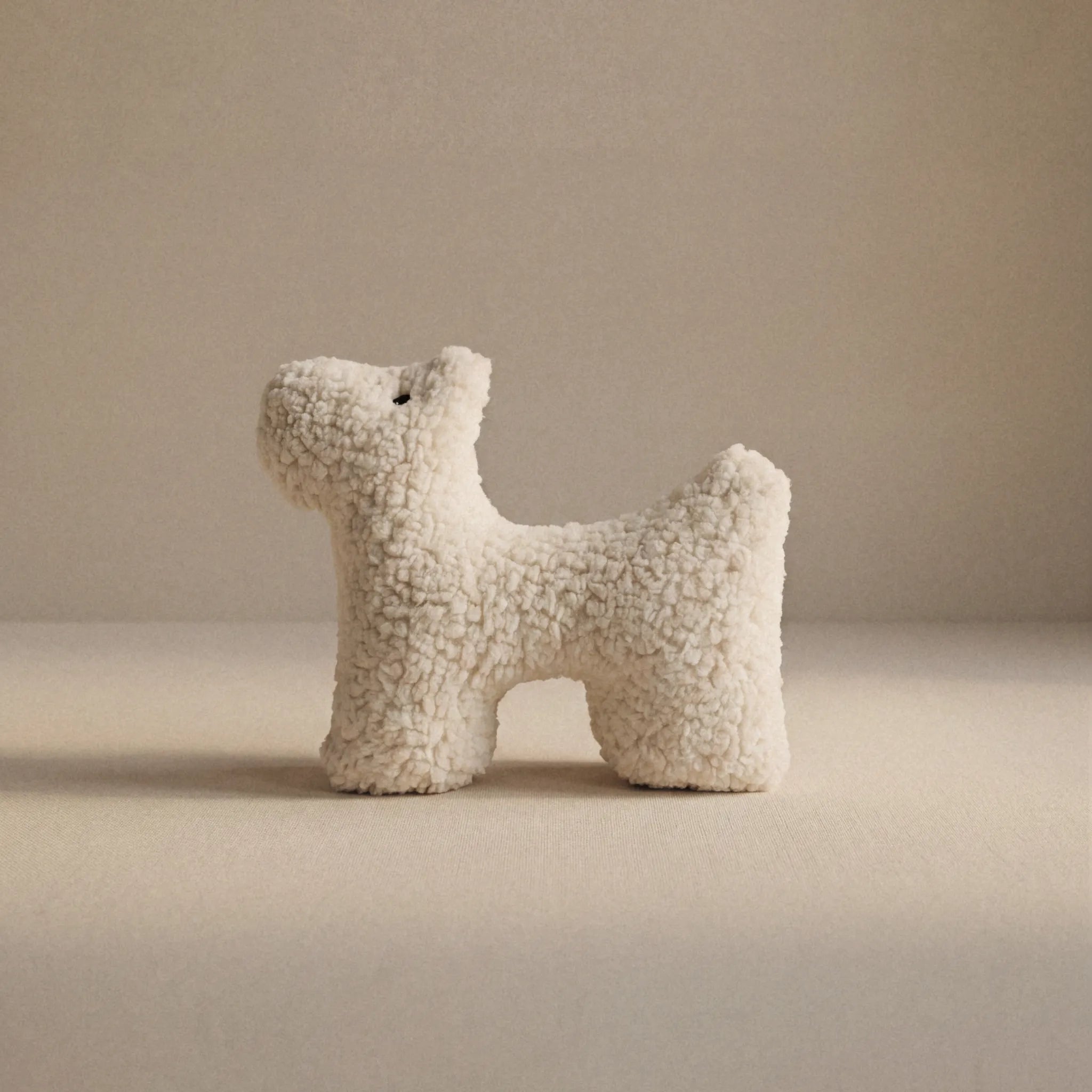A small wool plush pet toy featuring a bouclé loop textured material, standing on a neutral beige background.