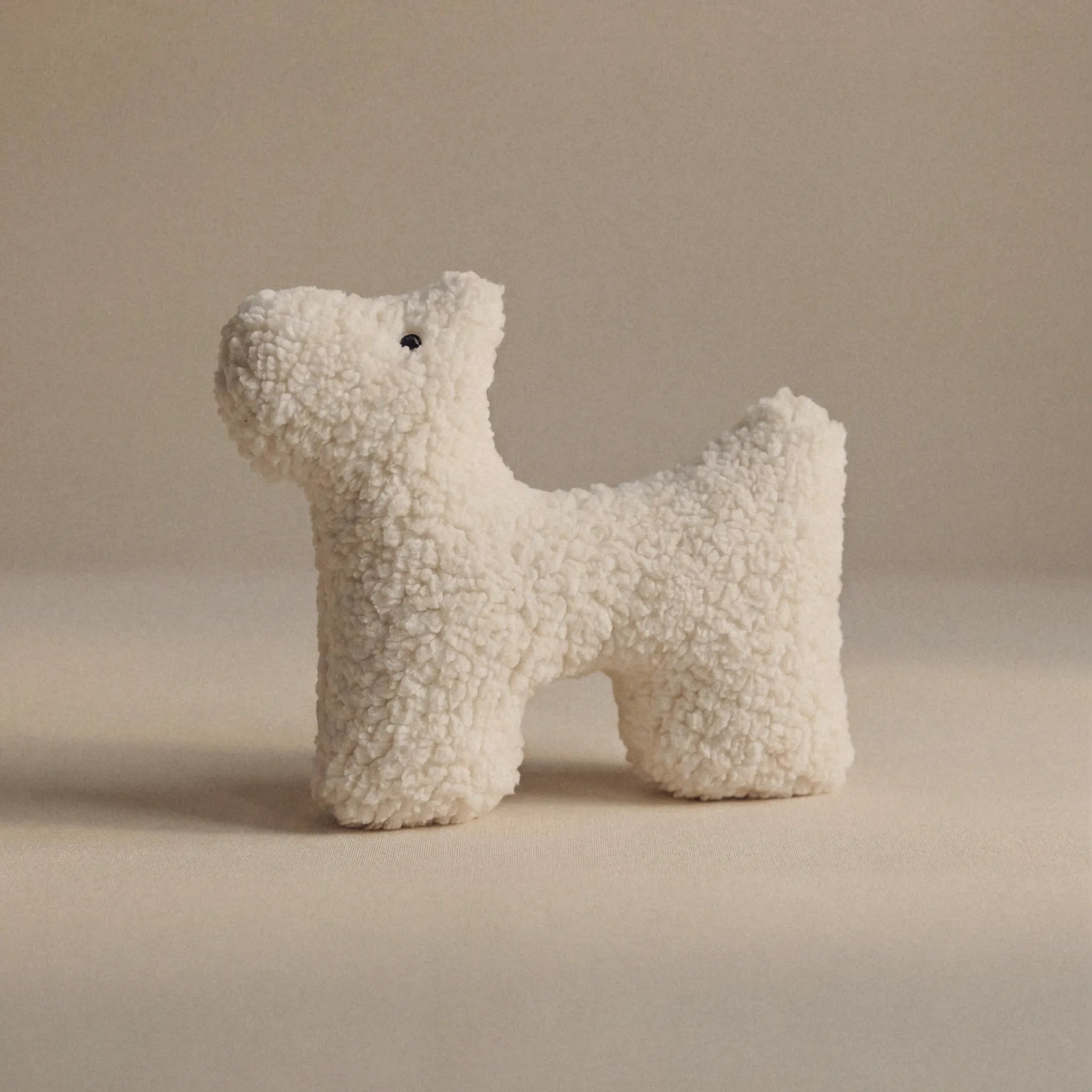 A small wool plush pet toy featuring a bouclé loop textured material, standing on a neutral beige background.