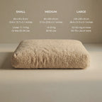 A beige 'Wool Lounge Bouclé Pet Bed' shown on a neutral beige background, with size information for Small, Medium, and Large sizes printed above it.