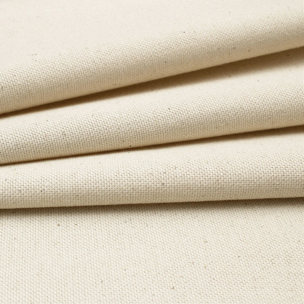 Close-up of cotton canvas fabric with a visible woven texture and subtle warm beige undertones.