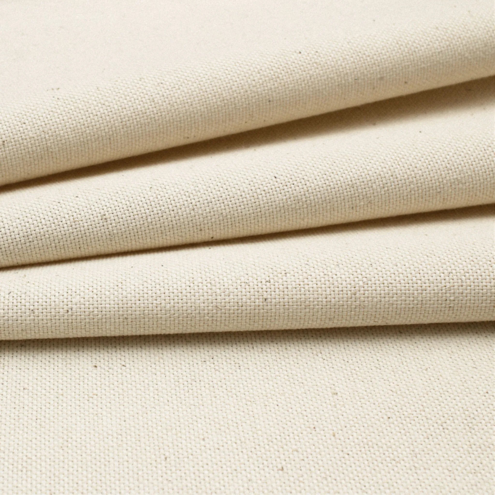 Close-up of cotton canvas fabric with a visible woven texture and subtle warm beige undertones.